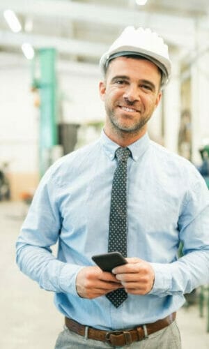Businessman talking on phone in factory. Businessman talking on phone in factory.